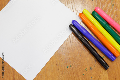 A set of colored markers and a sheet of white paper on the table.