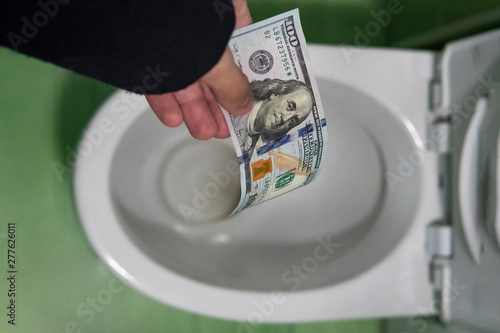 Fotografie concept of senseless waste of money, loss, useless waste, large water costs, Flushing one hundred dollars down the toilet