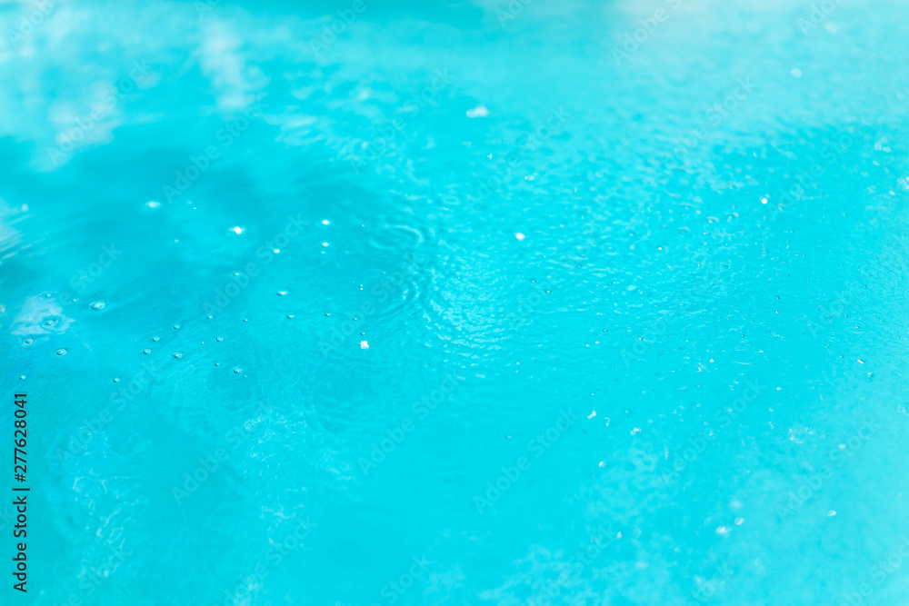 Closeup of colorful blue pool surface with bubbles and view of floor in spa hot spring tub abstract background