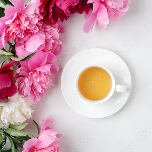 Creative layout with pink white peonies flowers and cup of tea on bright table. Spring Seasonal valentine, woman, mother, 8 march holiday, romance breakfast