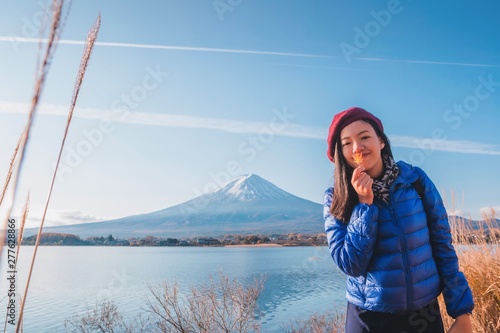 Asian beautiful smiling woman tourists are traveling and feel happy in the Field of dry grass with Mt Fuji in the morning on the lake kawaguchiko  Japan.On autumn season background.