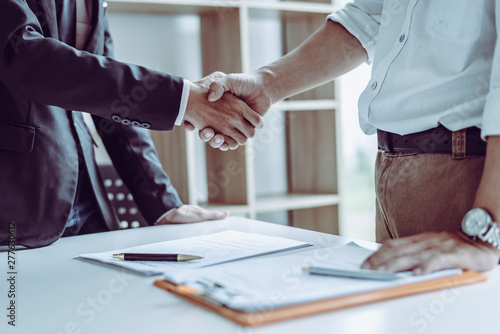 Middle age Asian partner lawyers attorneys shaking hands after discussing a contract agreement done.