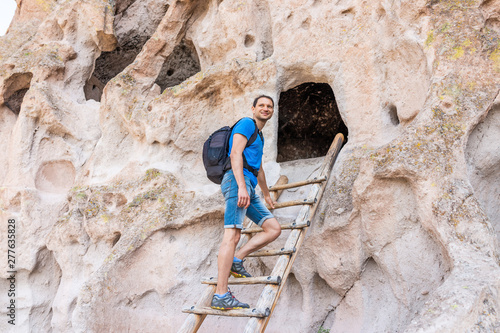 Man tourist happy climbing ladder on Main Loop trail path in Bandelier National Monument in New Mexico during summer by canyon cliff © Kristina Blokhin