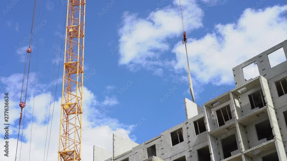 construction crane lifts the wall panel on the house under construction. At the construction site works tower crane. The process of building a multi-storey residential building. construction crane lifts the wall panel on the house under construction. At the construction site works tower crane. The process of building a multi-storey residential building.