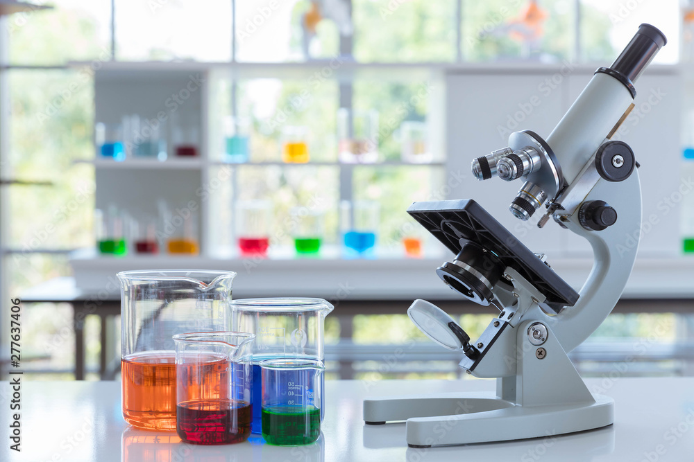 The scientific microscope with the scientific glassware on the white table. The scientific microscope with the scientific glassware on the white table.
