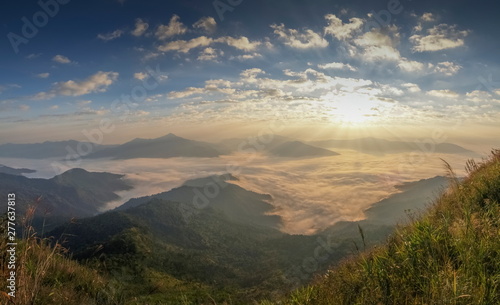 sunrise at Pha Tang, mountain view misty morning of top hill above Mekong river around with sea of fog and yellow sun light in the sky background, popular nature attraction in Chiang Rai, Thailand.