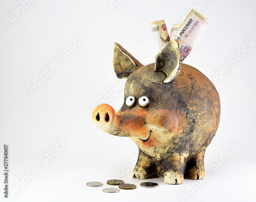 Clay piggy Bank with coins and paper money.