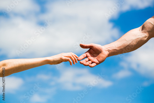 Hands of man and woman reaching to each other, support. Hands of man and woman on blue sky background. Giving a helping hand. Lending a helping hand. Solidarity, compassion, and charity, rescue © Yevhen