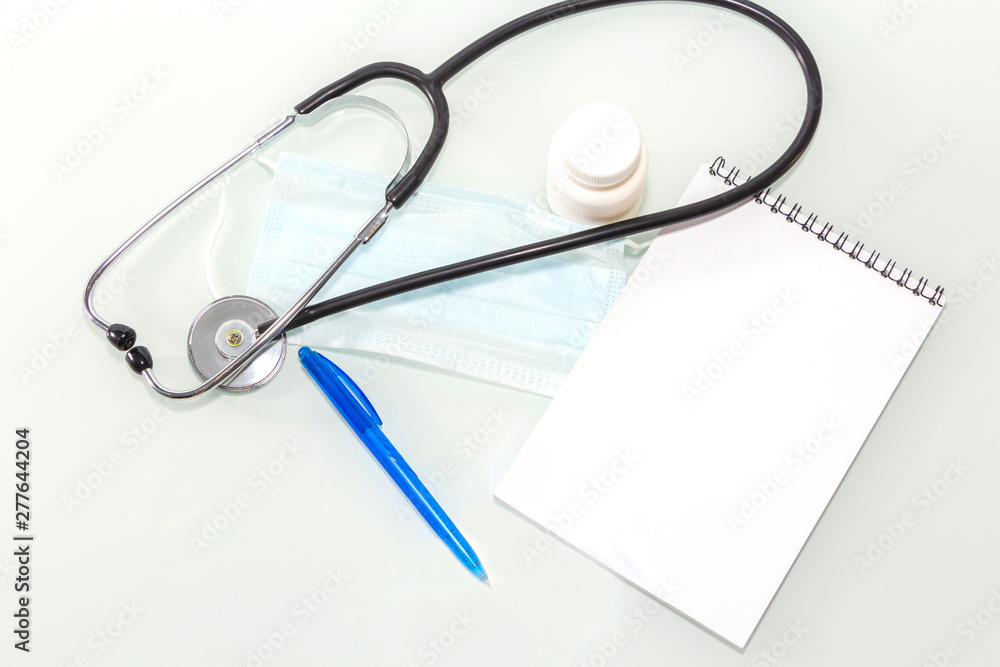 Stethoscope in the office of doctors.Top view of doctor's desk table, blank paper on clipboard with pen. Copy space. Stethoscope in the office of doctors.Top view of doctor's desk table, blank paper on clipboard with pen. Copy space.