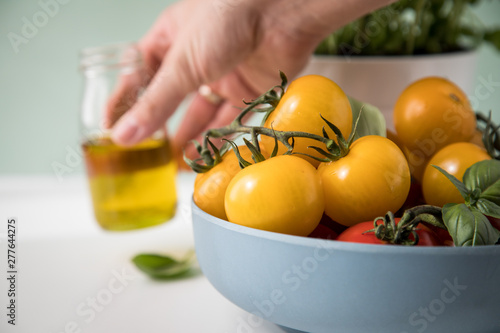 Frau isst rote und gelbe Tomaten mit Basilikum und Olivenöl 