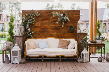 Coziness and style. Modern event design. Lounge and photo zone and european traditional wedding ceremony decoration outdoors in the restaurant before the reception.