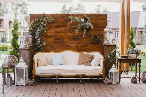 Coziness and style. Modern event design. Lounge and photo zone and european traditional wedding ceremony decoration outdoors in the restaurant before the reception.