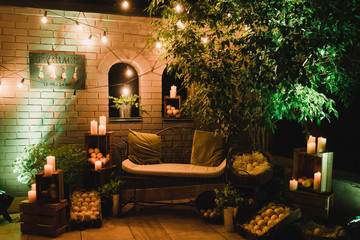Coziness and style. Modern event design. Lounge and photo zone and european traditional wedding ceremony decoration outdoors in the restaurant in the evening.