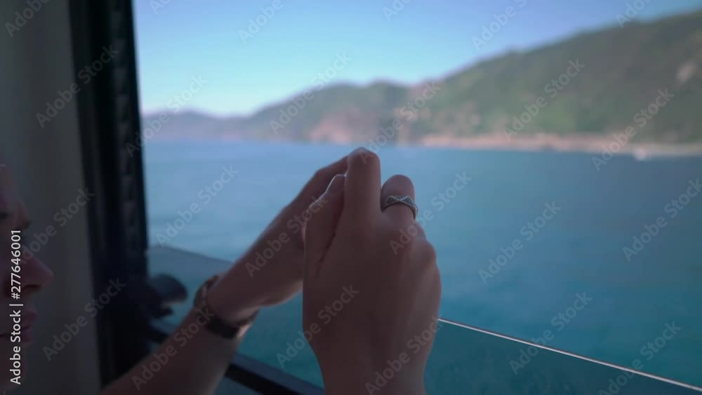 Blond Woman Taking Video of the Beautiful Landscape in Italy, on her smartphone. on a Boat
