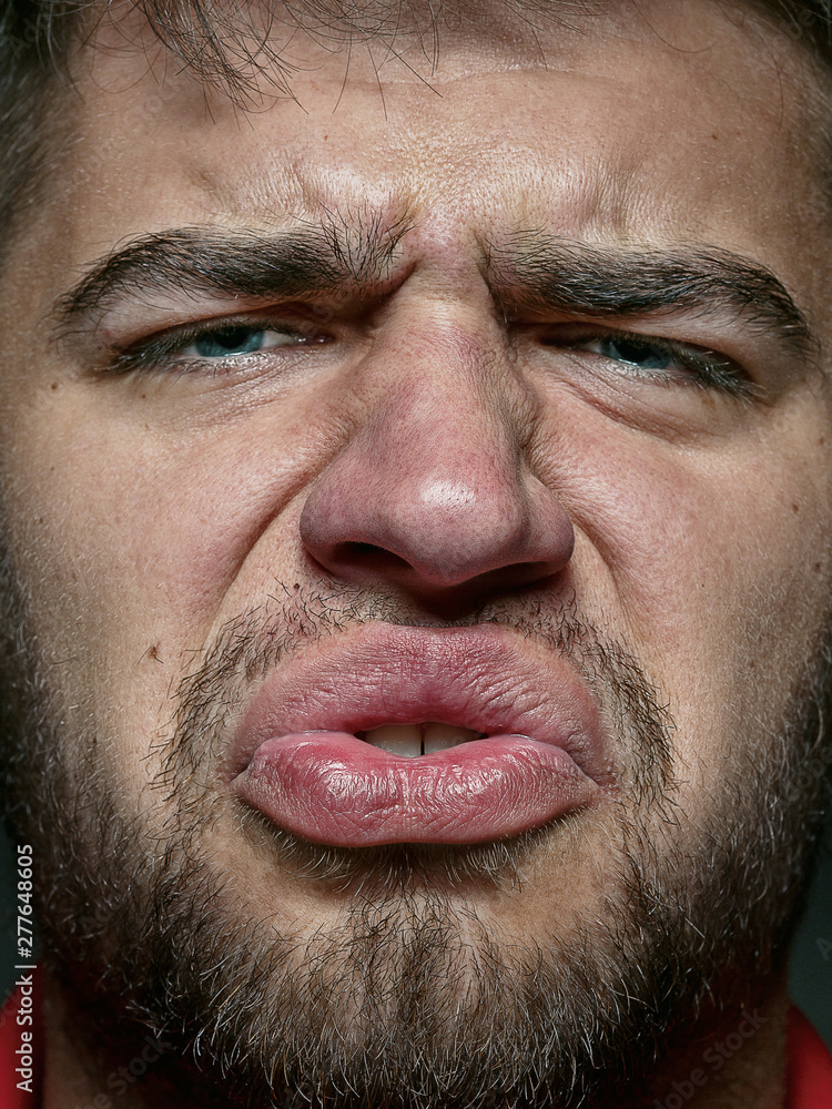 Obraz premium Close up portrait of young and emotional caucasian man. Highly detail photoshot of male model with well-kept skin and bright facial expression. Concept of human emotions. Disgusting feeling.