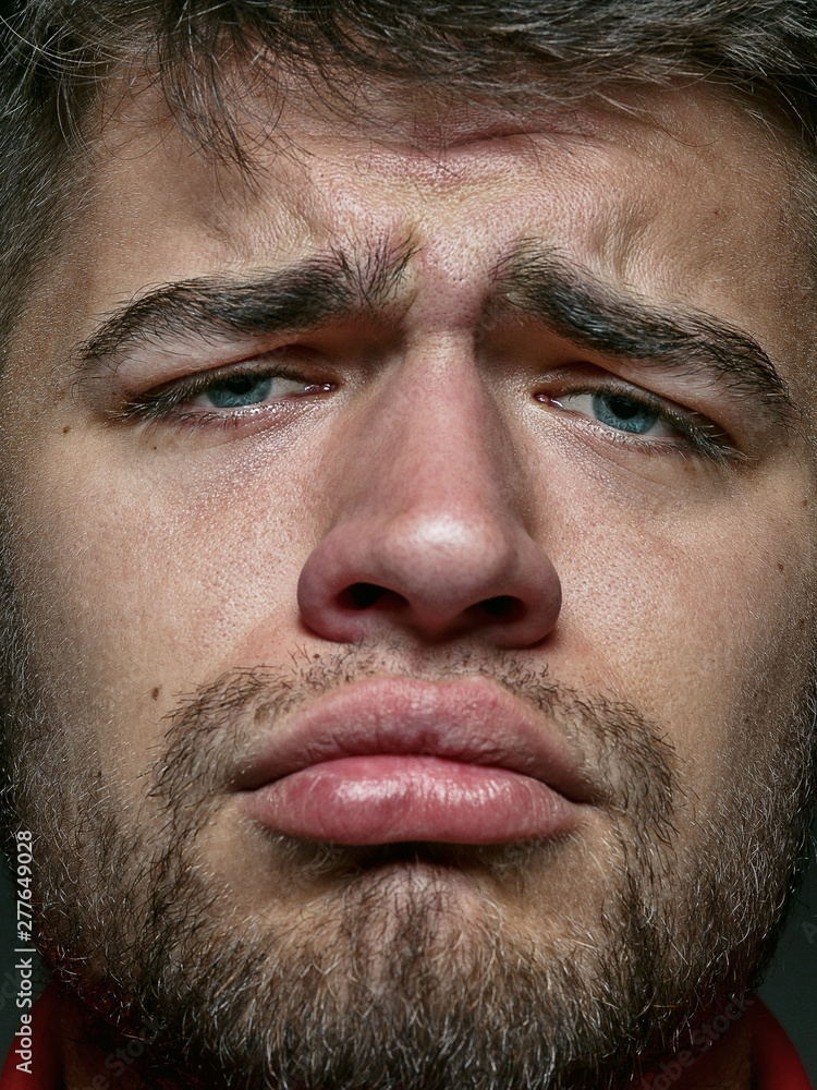 Obraz premium Close up portrait of young and emotional caucasian man. Highly detail photoshot of male model with well-kept skin and bright facial expression. Concept of human emotions. Looks sad and upset.