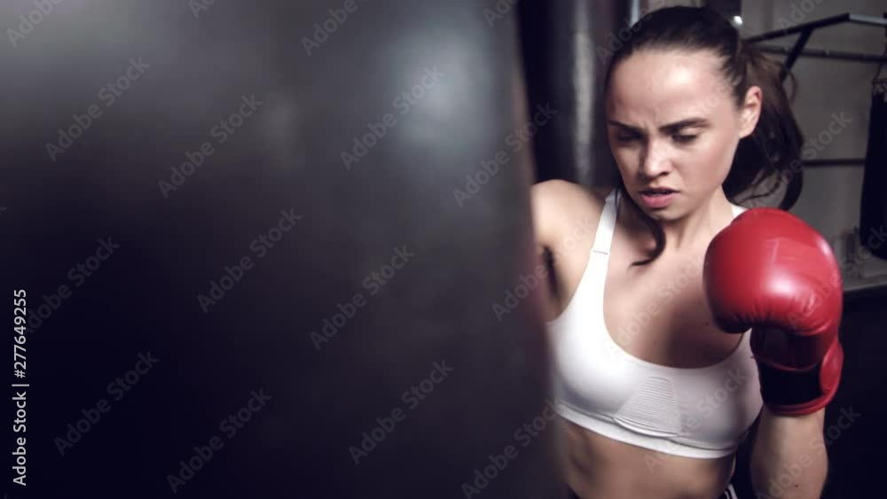 Female boxer hitting a huge punching bag at a boxing studio. Woman boxer training hard. Female boxer hitting a huge punching bag at a boxing studio. Woman boxer training hard.
