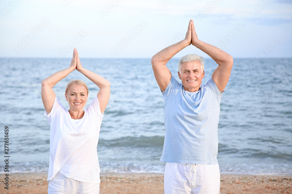 Mature couple practicing yoga at sea resort Mature couple practicing yoga at sea resort