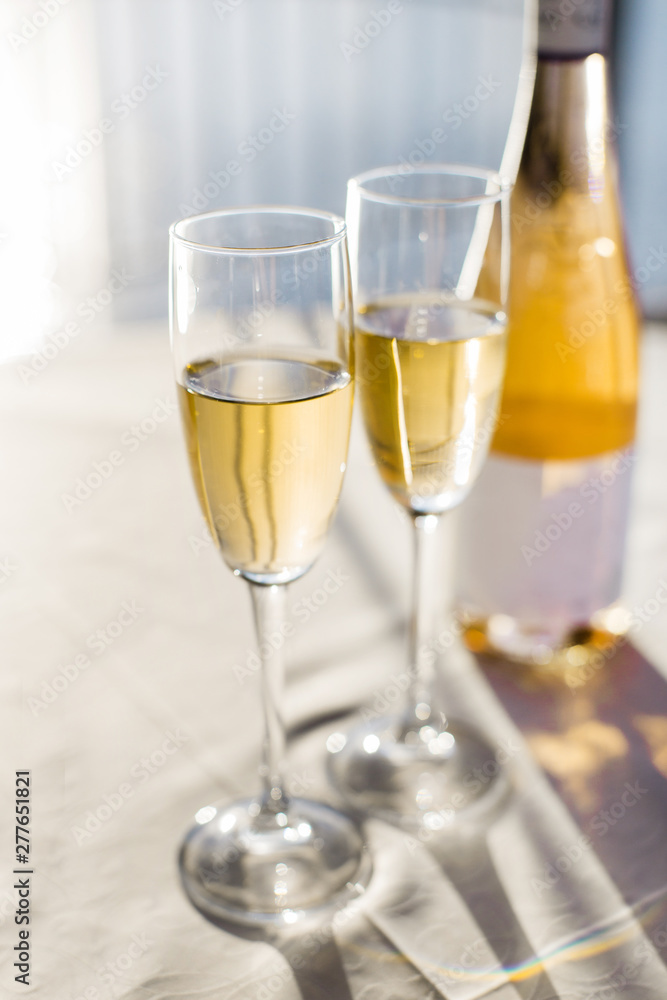 Champagne for romantic celebrations and enjoy for special moments. Two romantic glasses of sparkling champagne alongside a bottle in copy space to celebrate a wedding, anniversary, New year Champagne for romantic celebrations and enjoy for special moments. Two romantic glasses of sparkling champagne alongside a bottle in copy space to celebrate a wedding, anniversary, New year