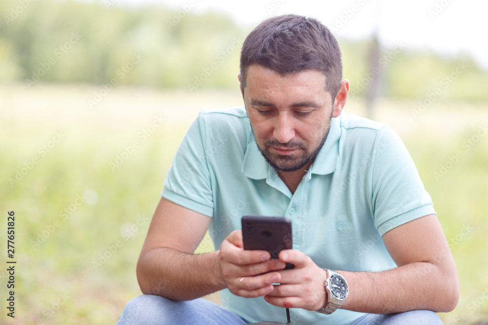 bearded man in light green shirt with phone outdoors on summer day bearded man in light green shirt with phone outdoors on summer day