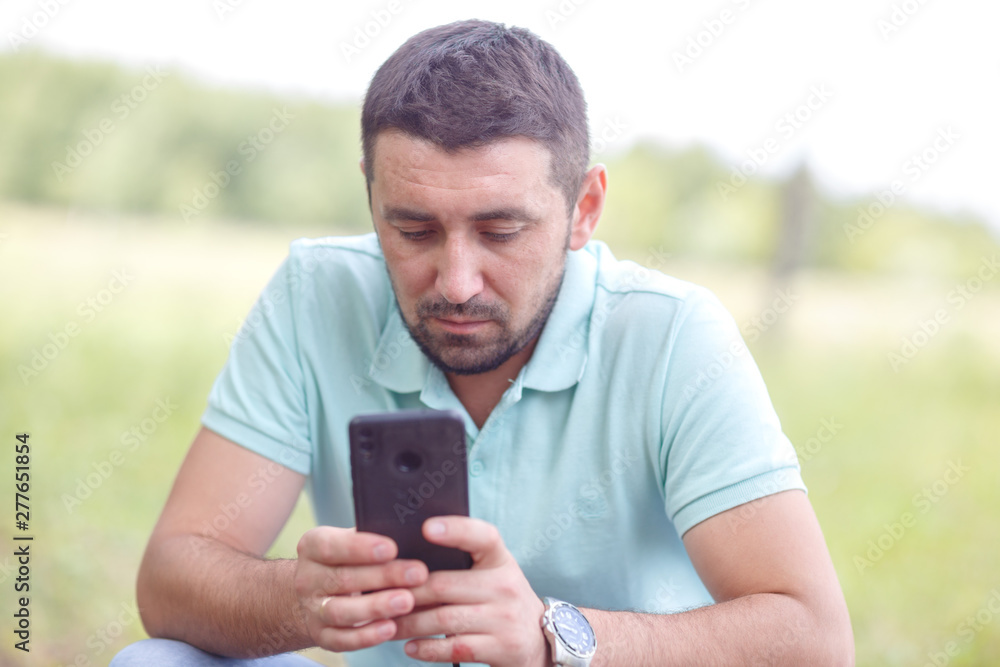 bearded man in light green shirt with phone outdoors on summer day bearded man in light green shirt with phone outdoors on summer day