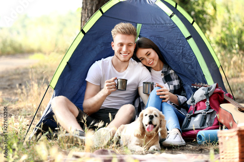 Young couple with cute dog spending weekend in forest