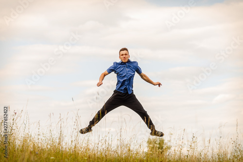 the jumping guy in the blue shirt outdoors on a summer day
