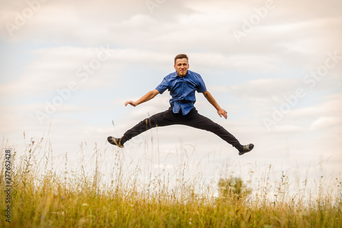 the jumping guy in the blue shirt outdoors on a summer day
