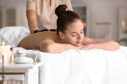 Young woman undergoing hot stone therapy in spa salon