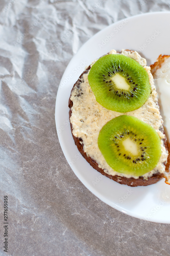 Delicious and healthy breakfast, kiwi sandwich and fried egg on a white plate, close-up, top view Delicious and healthy breakfast, kiwi sandwich and fried egg on a white plate, close-up, top view
