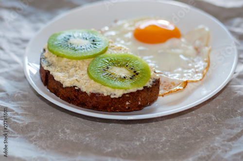 Delicious and healthy breakfast. Scrambled eggs and kiwi sandwich on a white plate, close-up, top view and side view