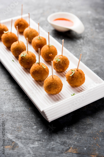 Crispy Veg lollipop recipe made using boiled potato with spices covered with corn flour and bread crumbs coating and then deep fried, served with toothpick or ice cream stock inserted in it with sauce photo