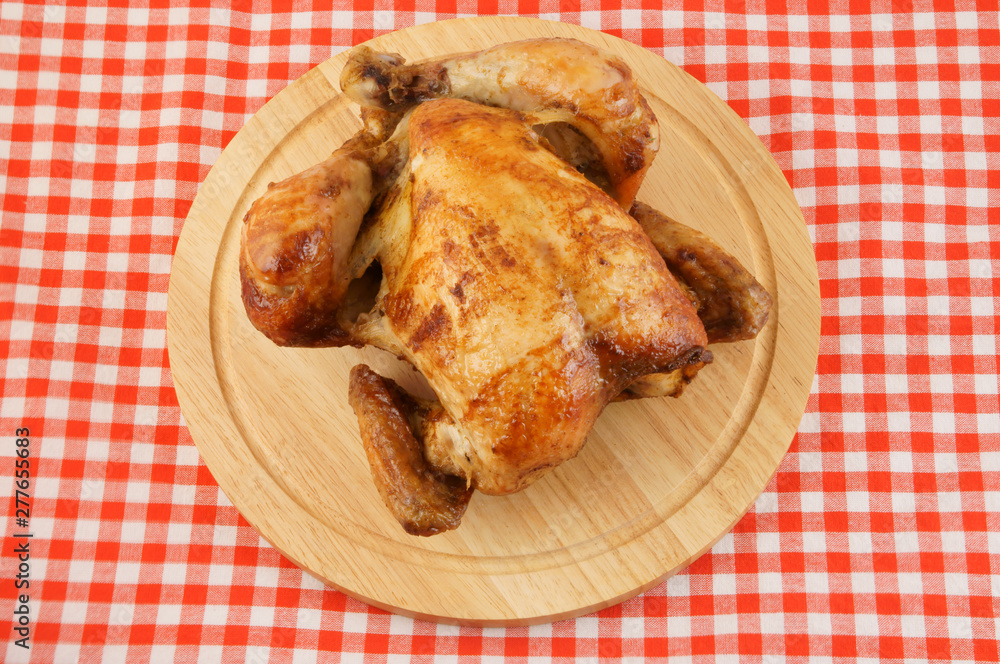 Roasted chicken on cutting board on tablecloth Roasted chicken on cutting board on tablecloth