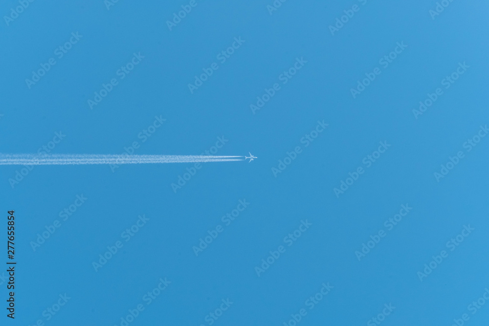 Jet airliner flying high in the sky leaves contrails in the clear blue sky Jet airliner flying high in the sky leaves contrails in the clear blue sky
