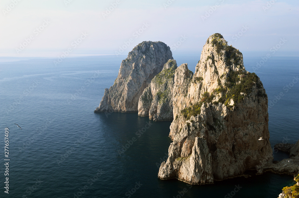 Picturesque cliffs of Faraglioni, protruding from the sea near the island of Capri.