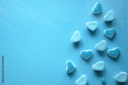 An assortment of colourful  festive sweets  lue marmalade in the shape of a heart on a blue background with a variety of caramels and candies  marshmallows. Abstract background. top view . copy space.