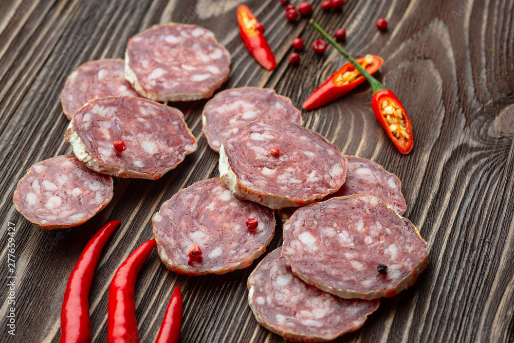 Sliced smoked salami with chilly pepper on wooden background. Sliced smoked salami with chilly pepper on wooden background.
