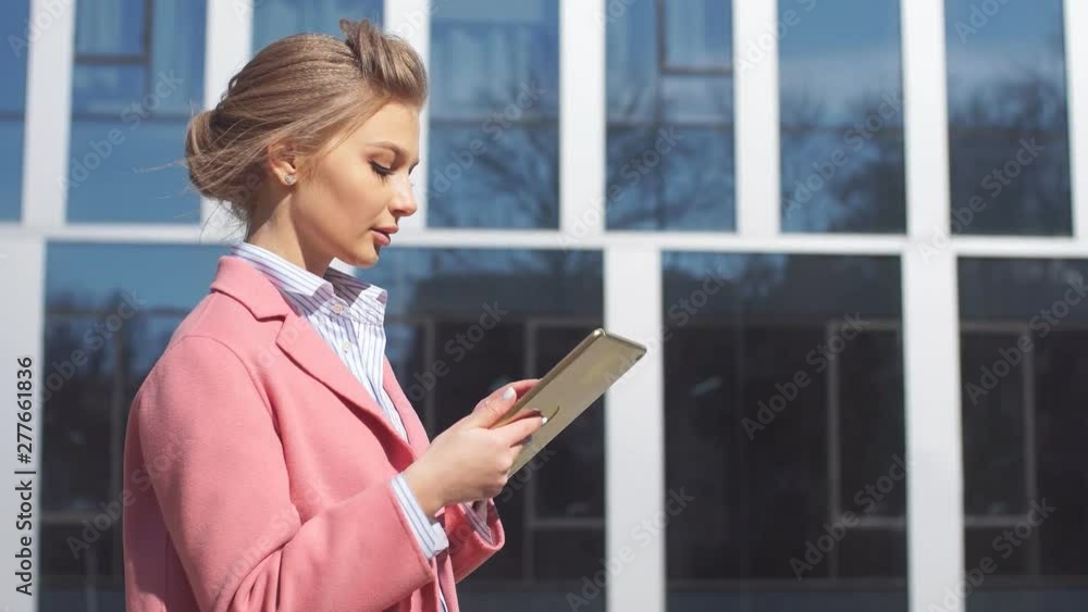 Young business woman uses a tablet on background of office building. Young business woman uses a tablet on background of office building.