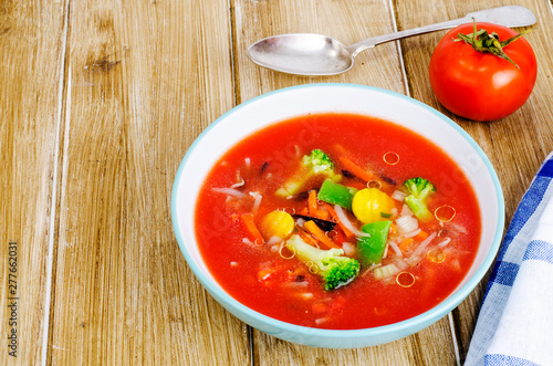 Spicy soup with tomatoes on wooden table
