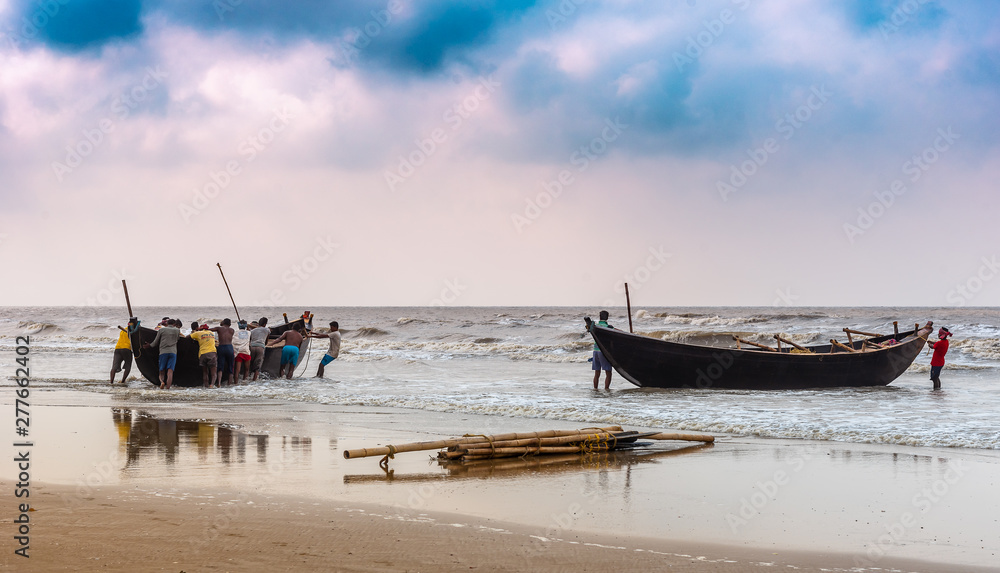 Digha, West Bengal, India. May 30,2019. Fishermen struggling to towing their fishing boat into the ocean before going for Fishing.