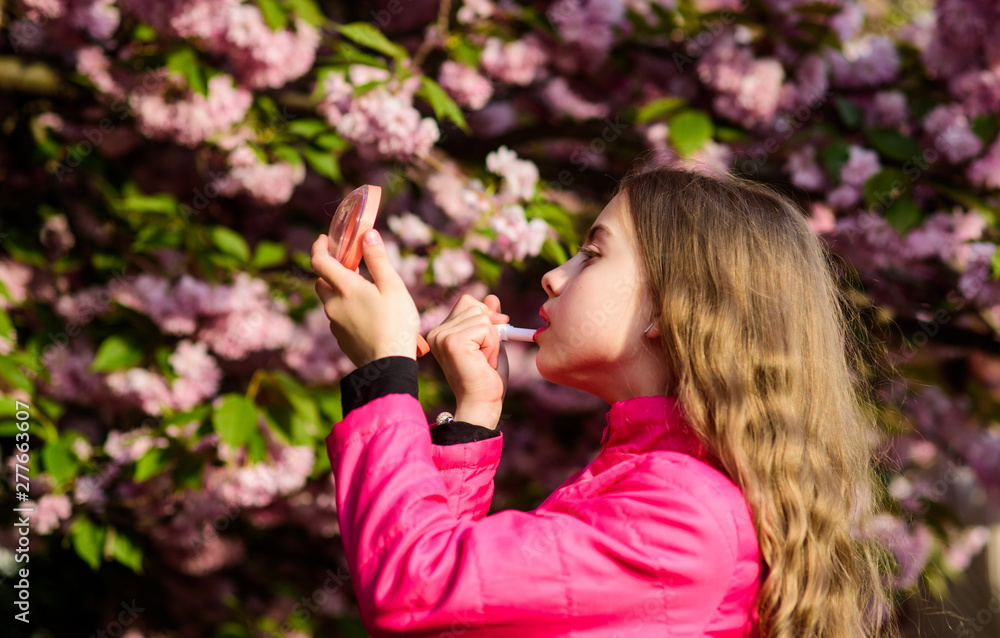 Smell of tender bloom. Sakura flower concept. Gorgeous flower and female beauty. Natural cosmetics for skin. Girl in cherry flower. Kid with lipstick makeup. Small girl child in spring flower bloom Smell of tender bloom. Sakura flower concept. Gorgeous flower and female beauty. Natural cosmetics for skin. Girl in cherry flower. Kid with lipstick makeup. Small girl child in spring flower bloom