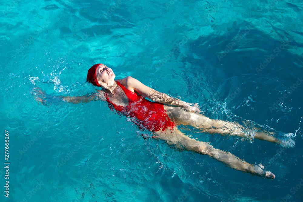 young woman in a red bathing suit swimming in the blue sea in Tahiti.