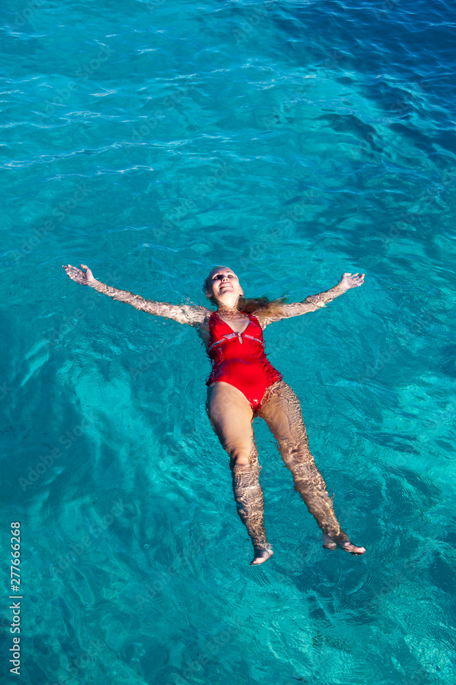 young woman in a red bathing suit swimming in the blue sea in Tahiti.