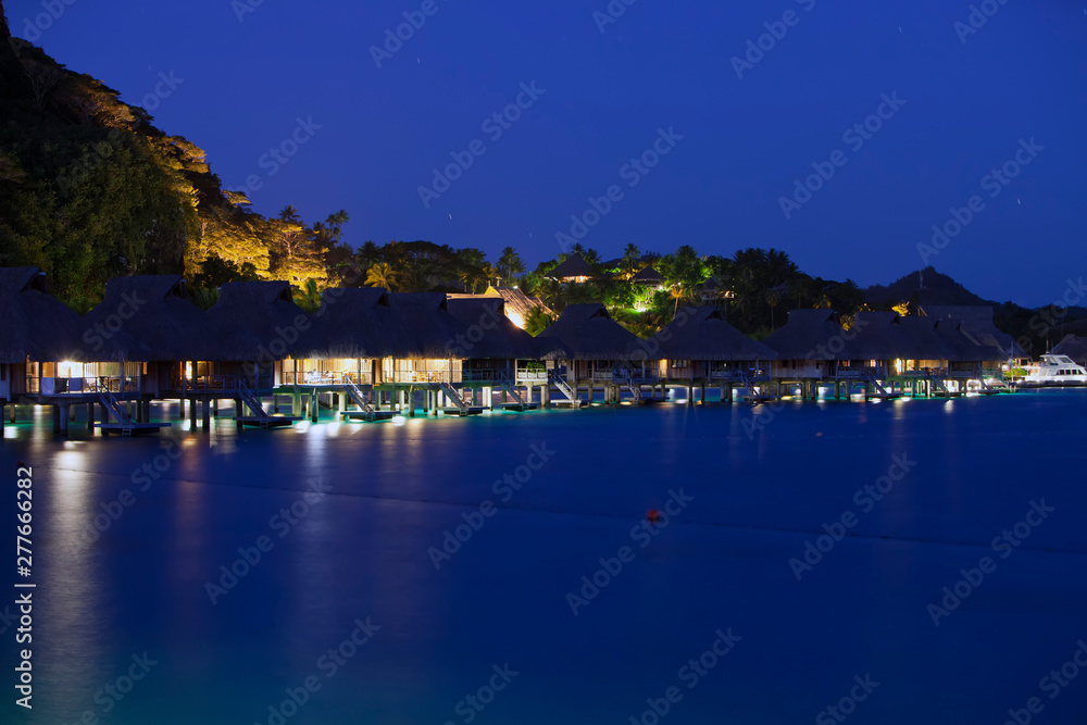 night landscape with houses over the water of the sea in backlight, Polynesia