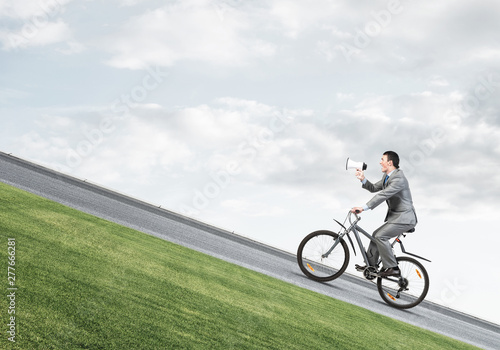 Businessman with megaphone in hand on bike