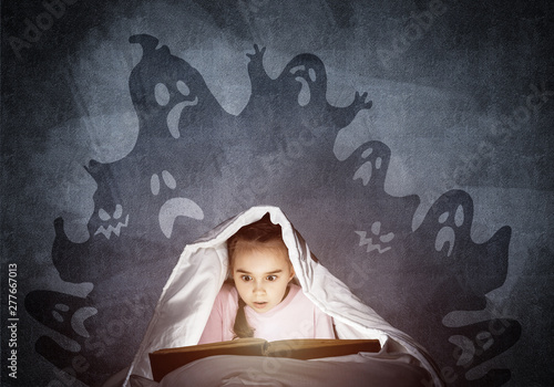 Scared little girl reading book in bed © adam121