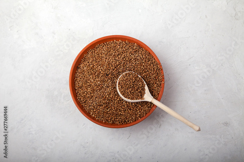 buckwheat with a wooden spoon in a clay bowl on a white background. superfood