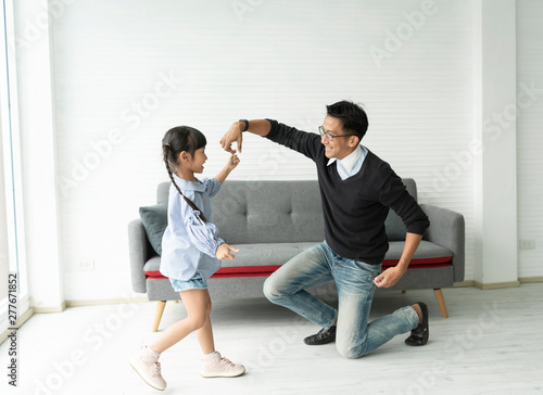 Fototapeta Naklejka Na Ścianę i Meble -  Happy asian father and daughter playing dance together in living room at home.