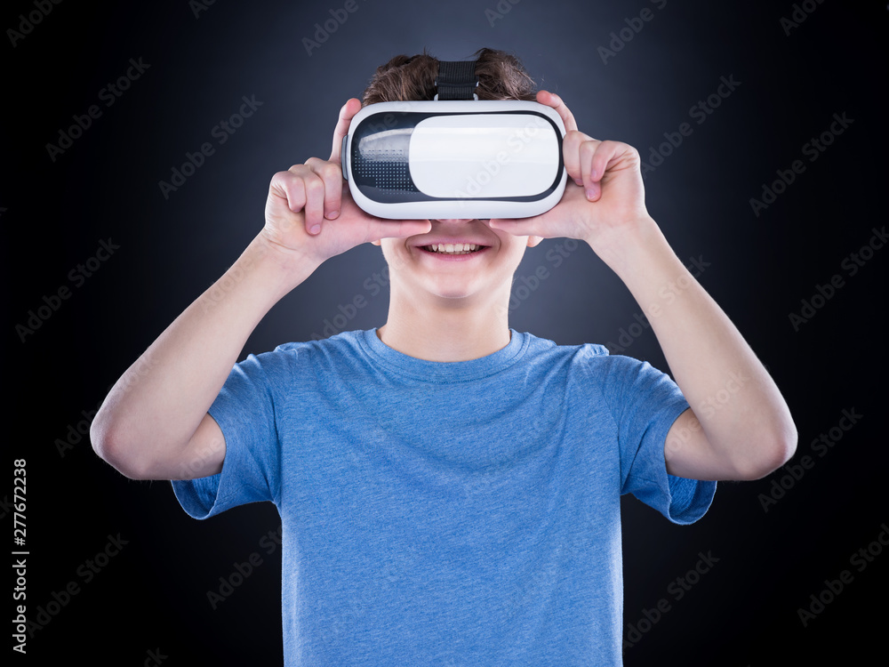 Happy teen boy wearing virtual reality goggles watching movies or playing  video games. Cheerful smiling teenager looking in VR glasses. Funny child  experiencing 3D gadget technology. Stock Photo | Adobe Stock