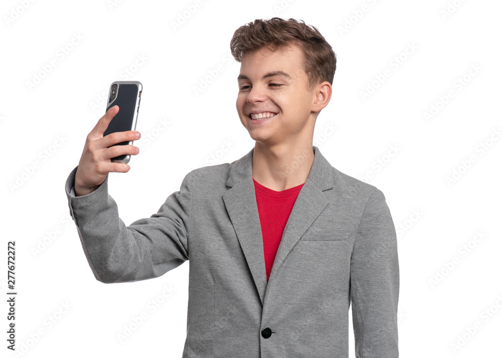 Portrait of Handsome Teen Boy talk to Mobile Phone, isolated on white background. Smiling Child standing and using Cell Phone. Cute modern Teenager taking Selfie photo on Smartphone. Portrait of Handsome Teen Boy talk to Mobile Phone, isolated on white background. Smiling Child standing and using Cell Phone. Cute modern Teenager taking Selfie photo on Smartphone.